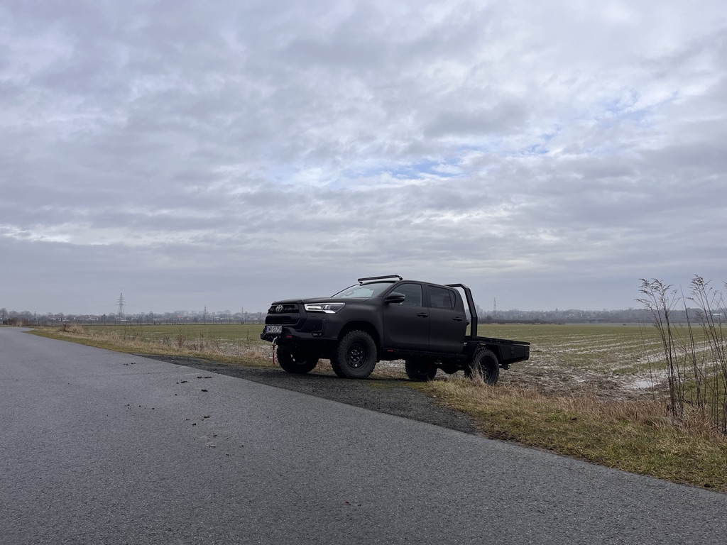 Toyota Hilux z zabudową flatbed w terenie – widok z boku