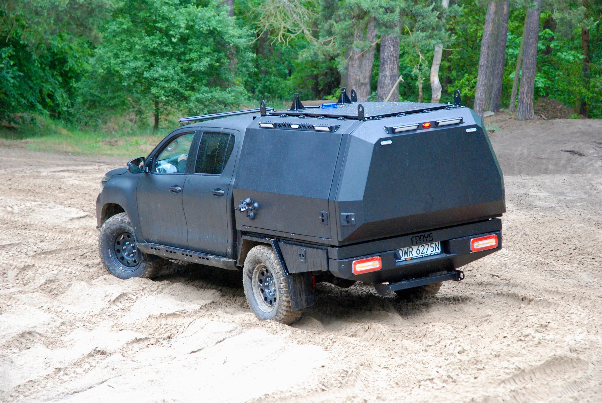Toyota Hilux z aluminiowym canopy Aliff w terenie piaszczystym przy lesie
