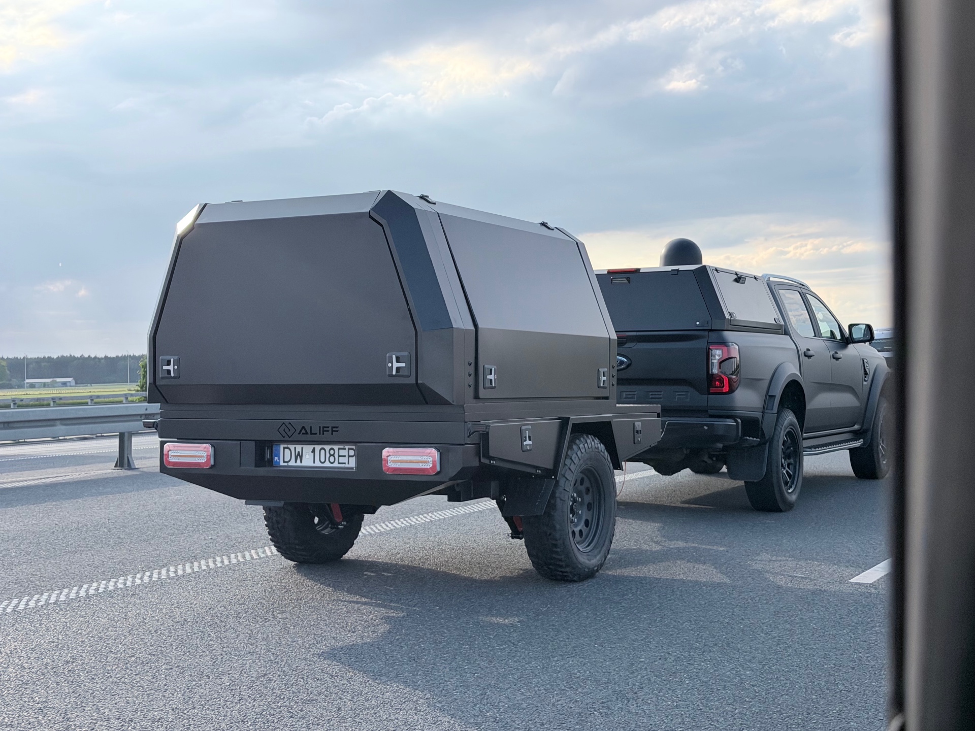 Gotowa przyczepka offroad Aliff za Fordem Ranger na autostradzie – aluminiowa zabudowa, hardtop, logo Aliff